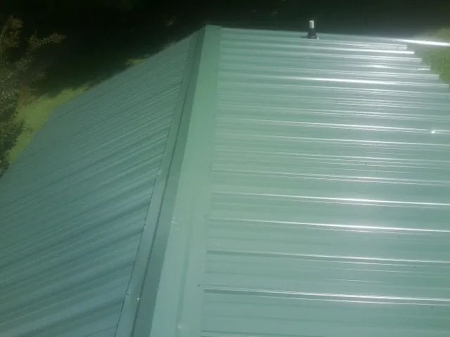 New green metal panels meeting at the ridge of a roof — Flat Roof Repair work by our crew in Grand Terrace