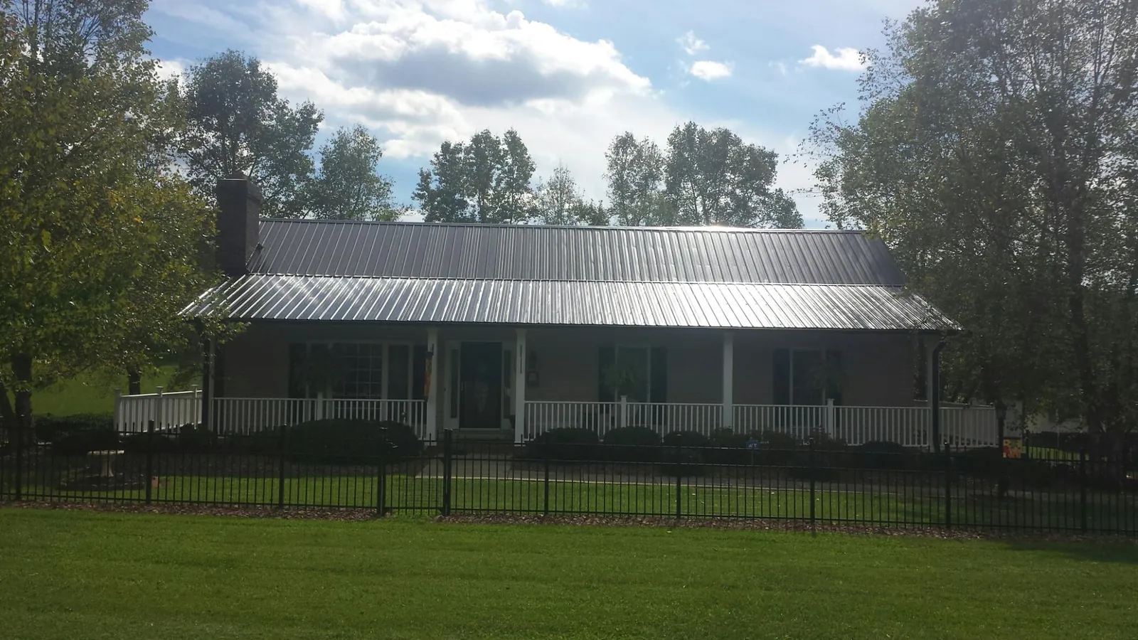Gray metal roof on a brick ranch with a full width front porch — Gutter Guard Installation work by our crew in Grand Terrace