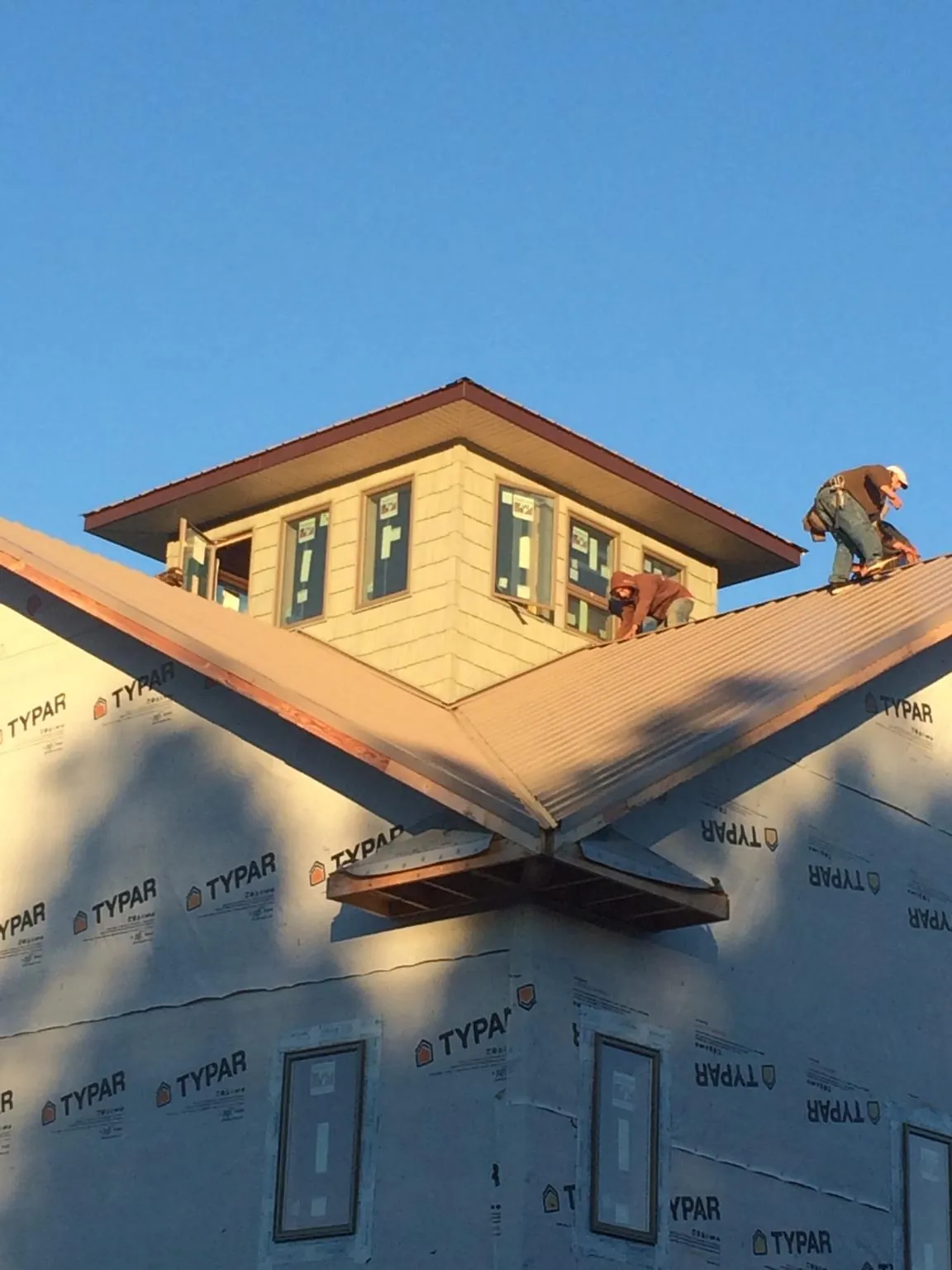 Roofers working around a rooftop cupola on a new metal roof at sunset — Roof Waterproofing in Grand Terrace by Roofing Brothers